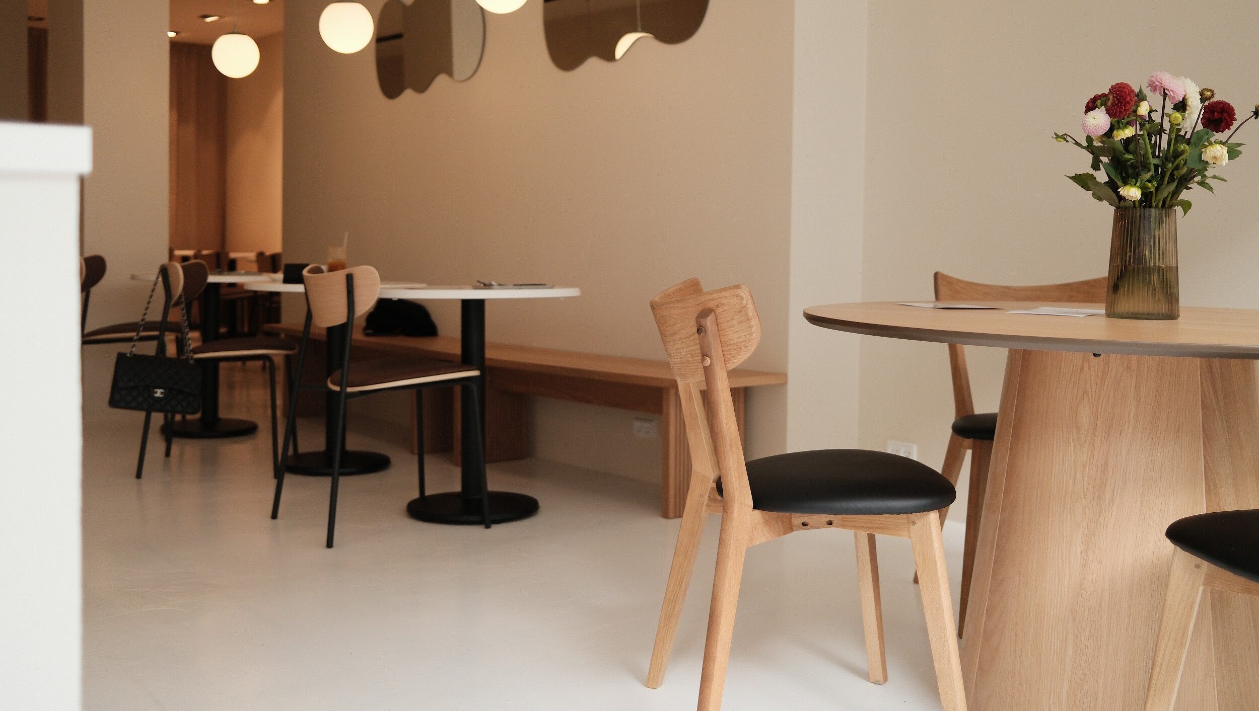 bright coffee shop interior with wooden tables and chairs and mirrors on the wall