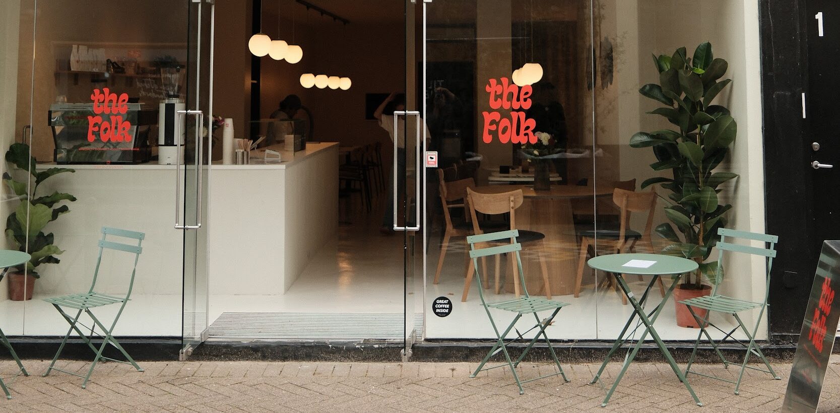 coffee shop front glass door with green outdoor chairs and tables